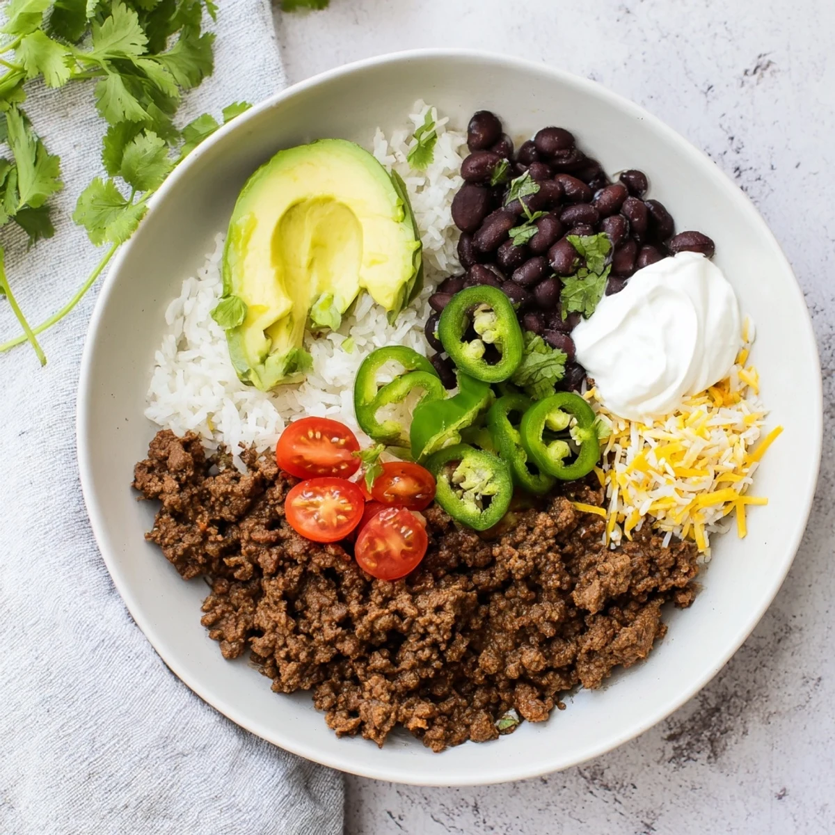 A close-up of a Beef Burrito Bowl, showcasing colorful fresh toppings atop seasoned beef.