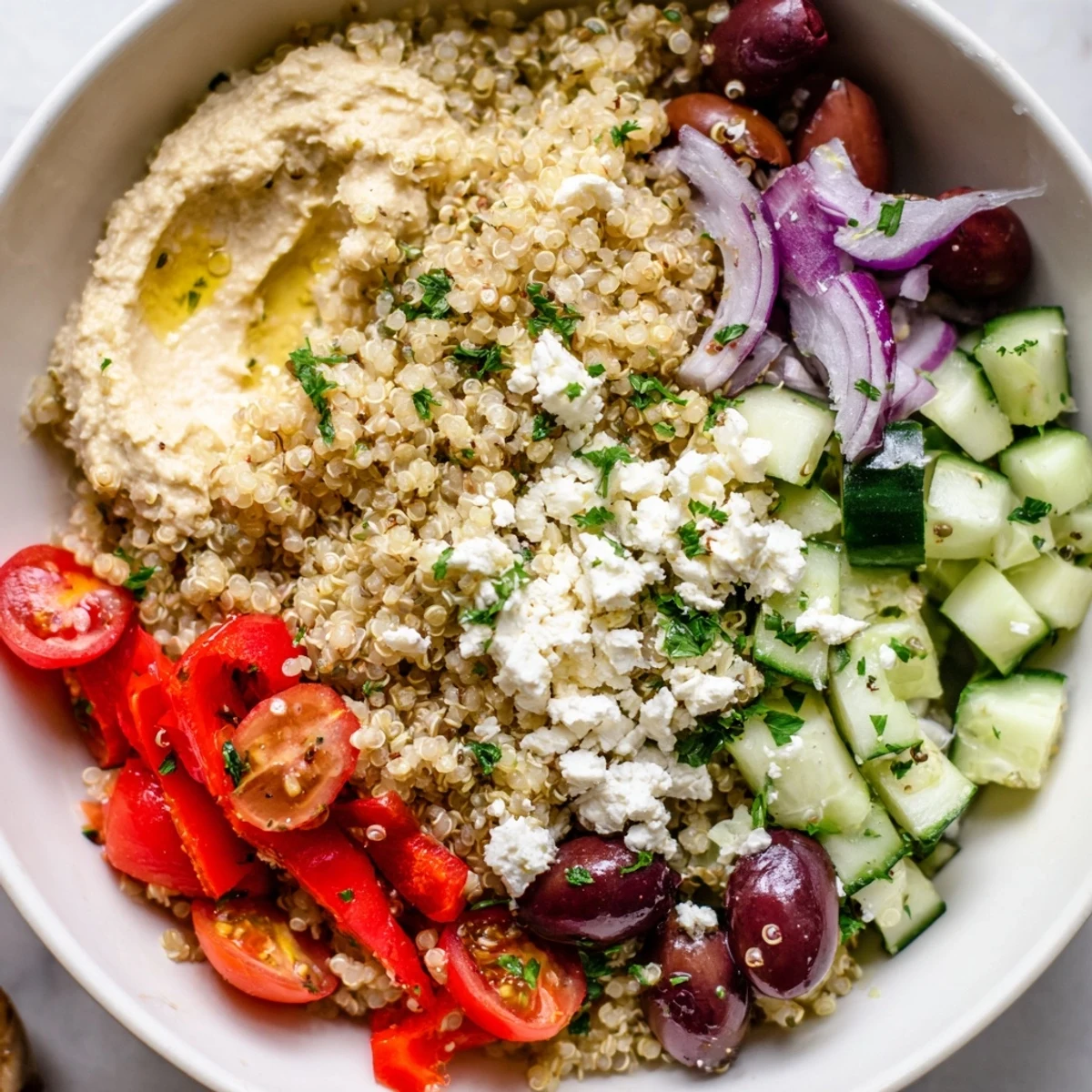 A colorful, gluten-free vegetarian bowl with creamy hummus and briny Kalamata olives.