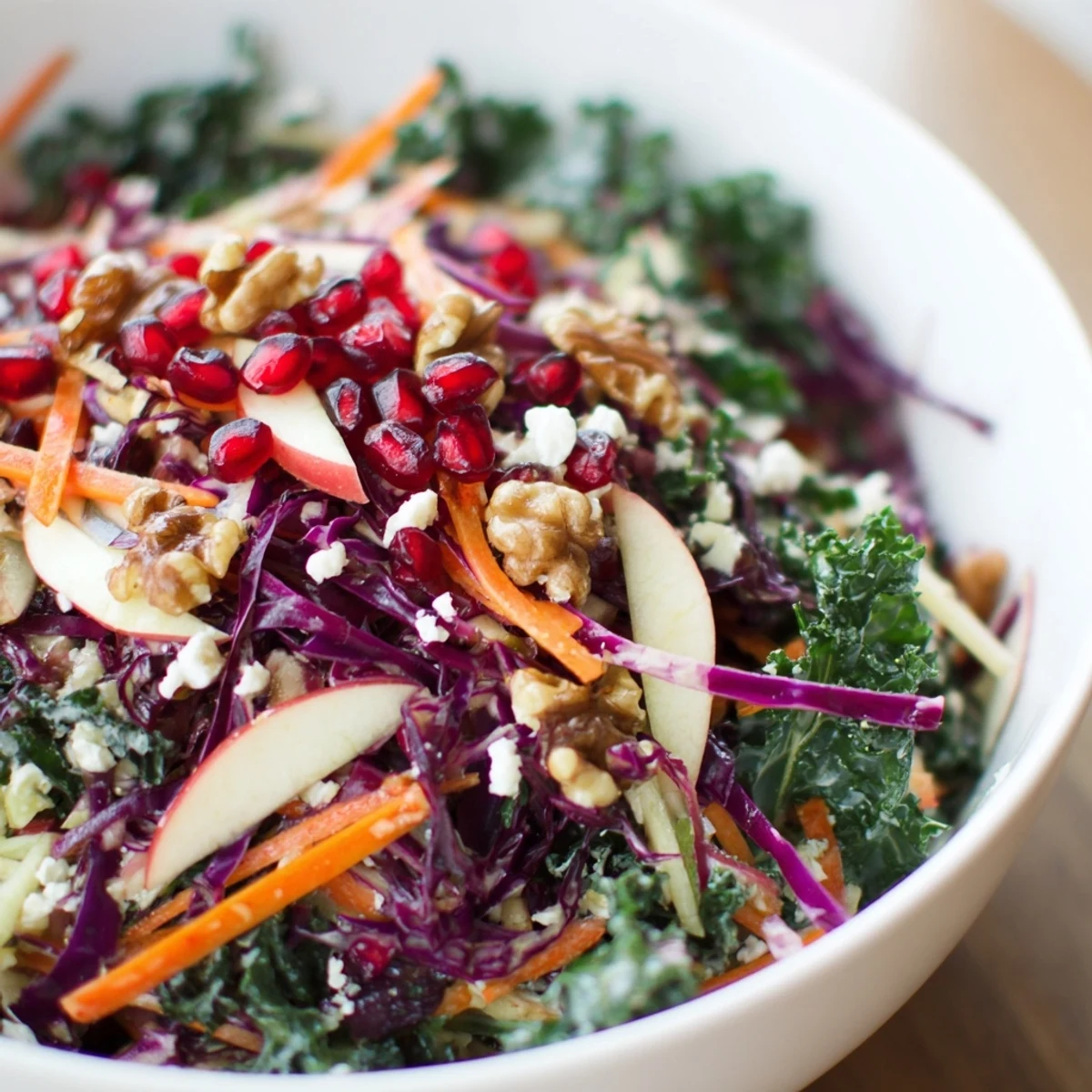 Freshly prepared Winter Salad Mix with kale, red cabbage, and bright pomegranate seeds topped with feta.