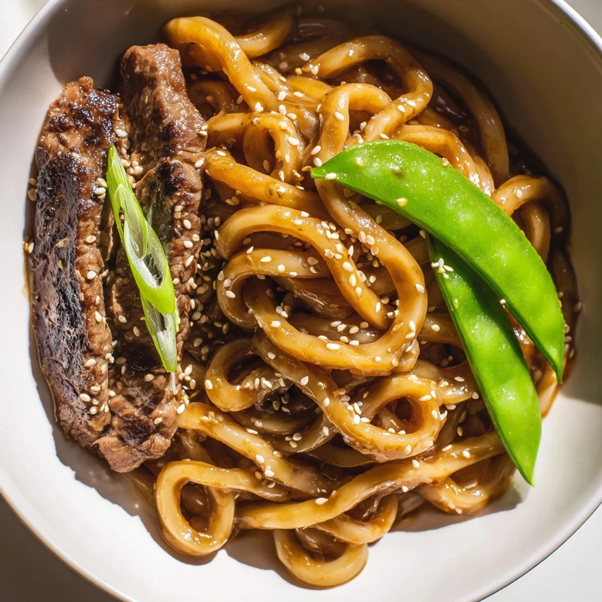 Steaming bowl of Spicy Beef Stir Fry with Udon Noodles, featuring tender beef and colorful vegetables in a glossy sauce.