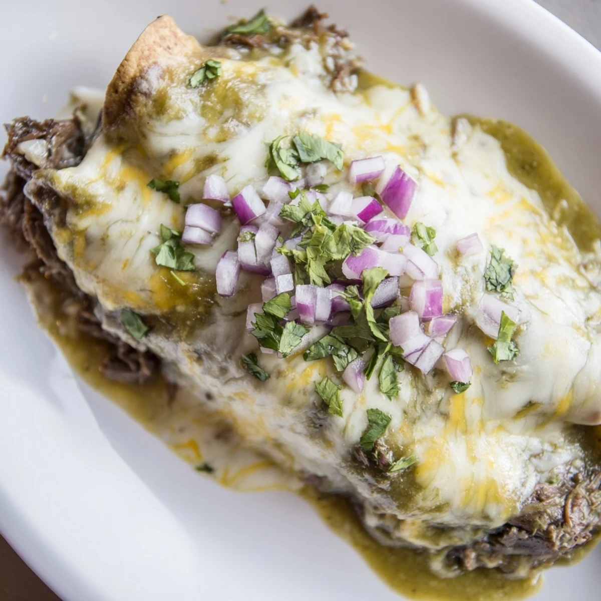 A close-up view shows a serving of Beef Enchiladas with Green Chili Sauce next to fresh lime wedges.