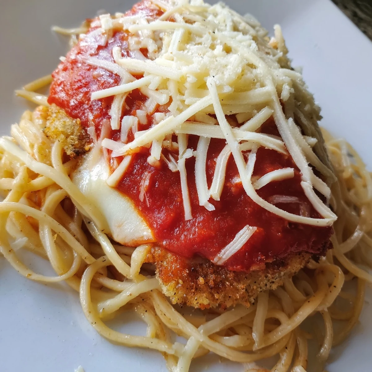 Classic Chicken Parmesan over spaghetti marinara, plated with extra Parmesan and a crisp green side salad.