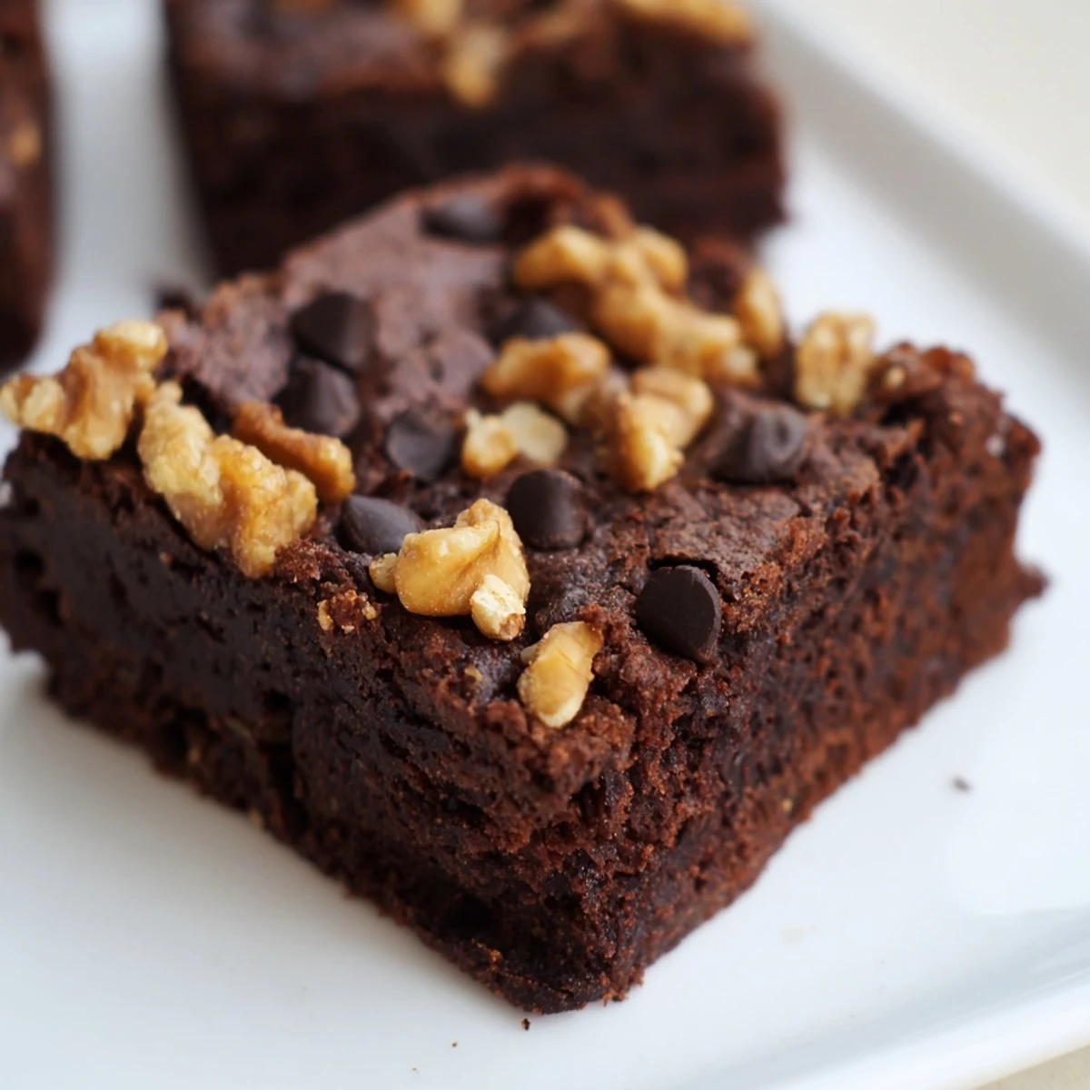 A close-up shot of Chocolate Fudge Brownies with Walnuts, displaying a rich, crackly top and fudgy interior texture.