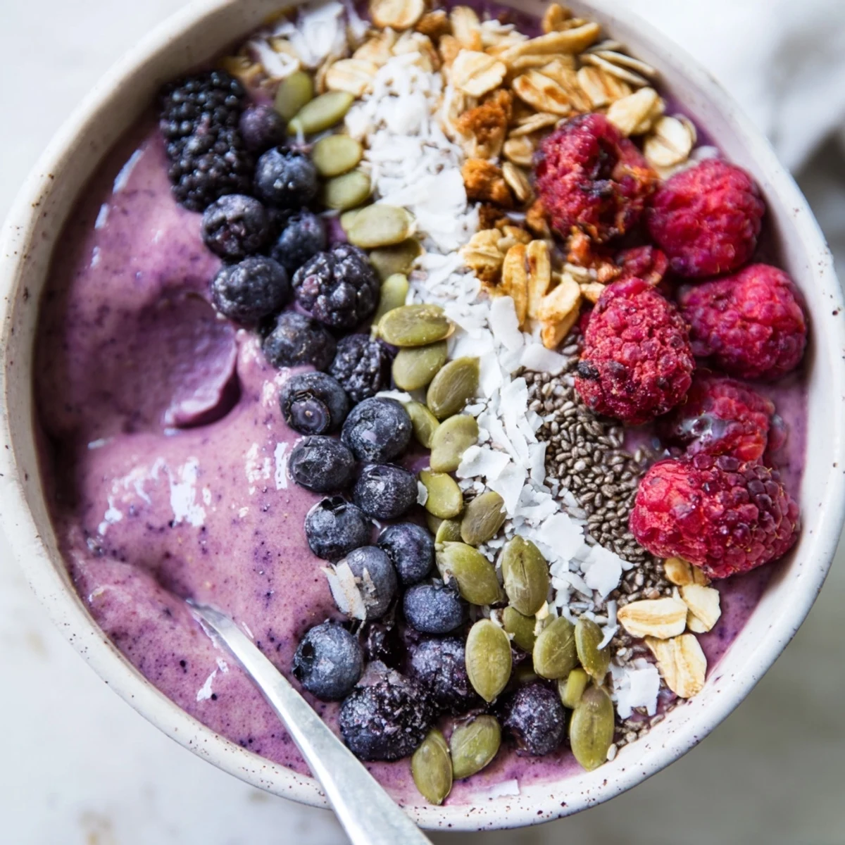 Close-up of Winter Berry Smoothie Bowl showing layered granola, chia, and pumpkin seeds adding crunch. 