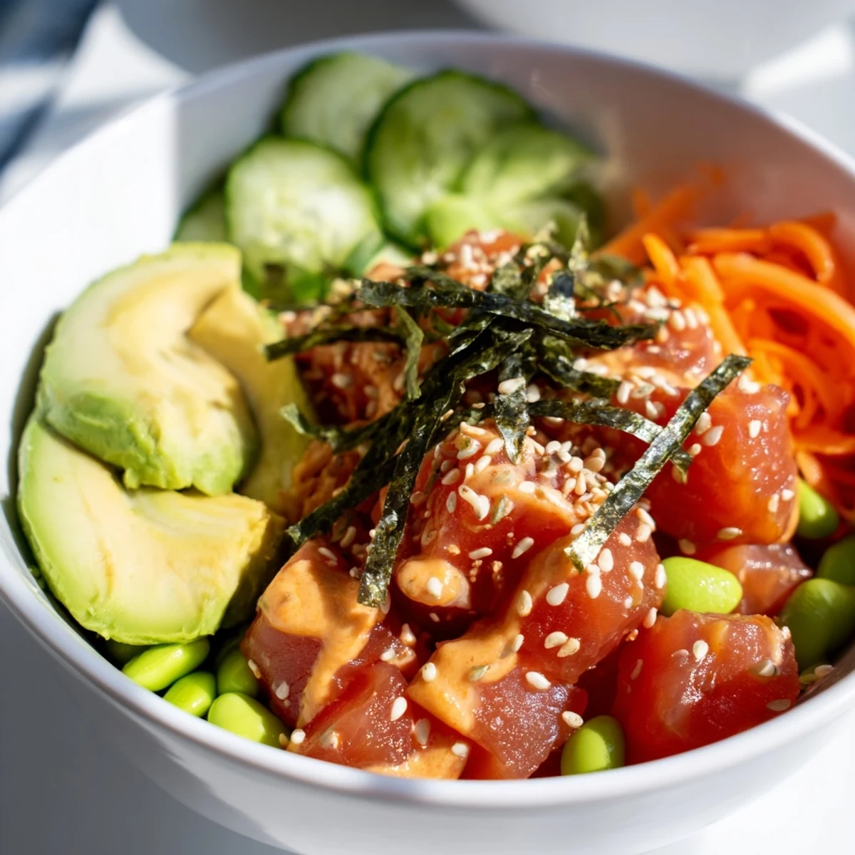 A vibrant Hawaiian-inspired Spicy Tuna Poke Bowl topped with edamame, julienned carrots, and sesame seeds for a satisfying, gluten-free lunch.