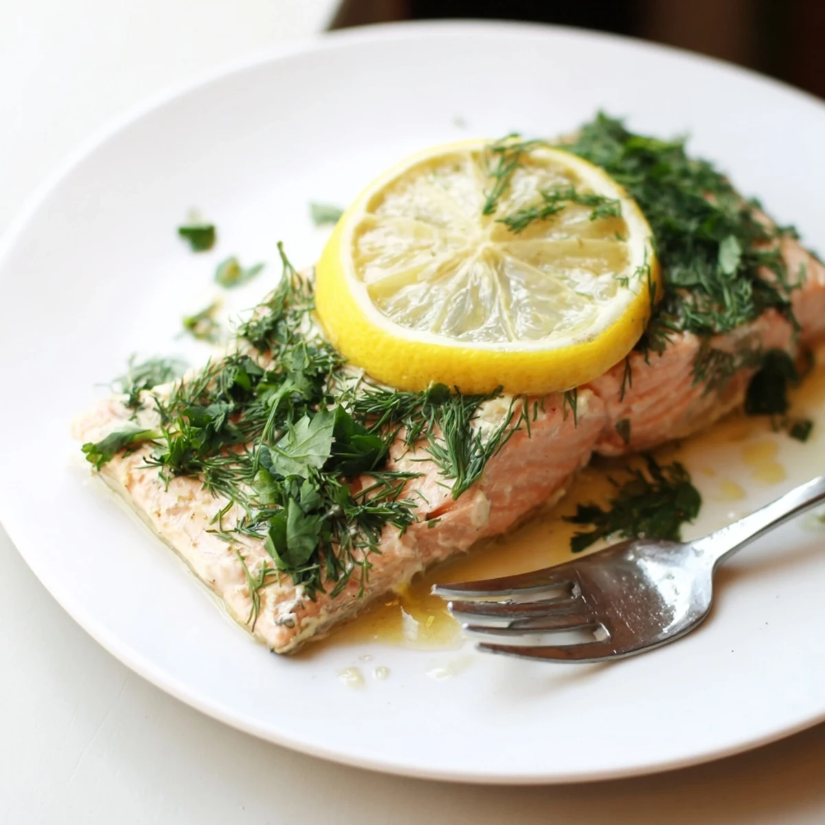 A close-up of Baked Salmon with Lemon garnished with dill and lemon wedges, flaky and moist.
