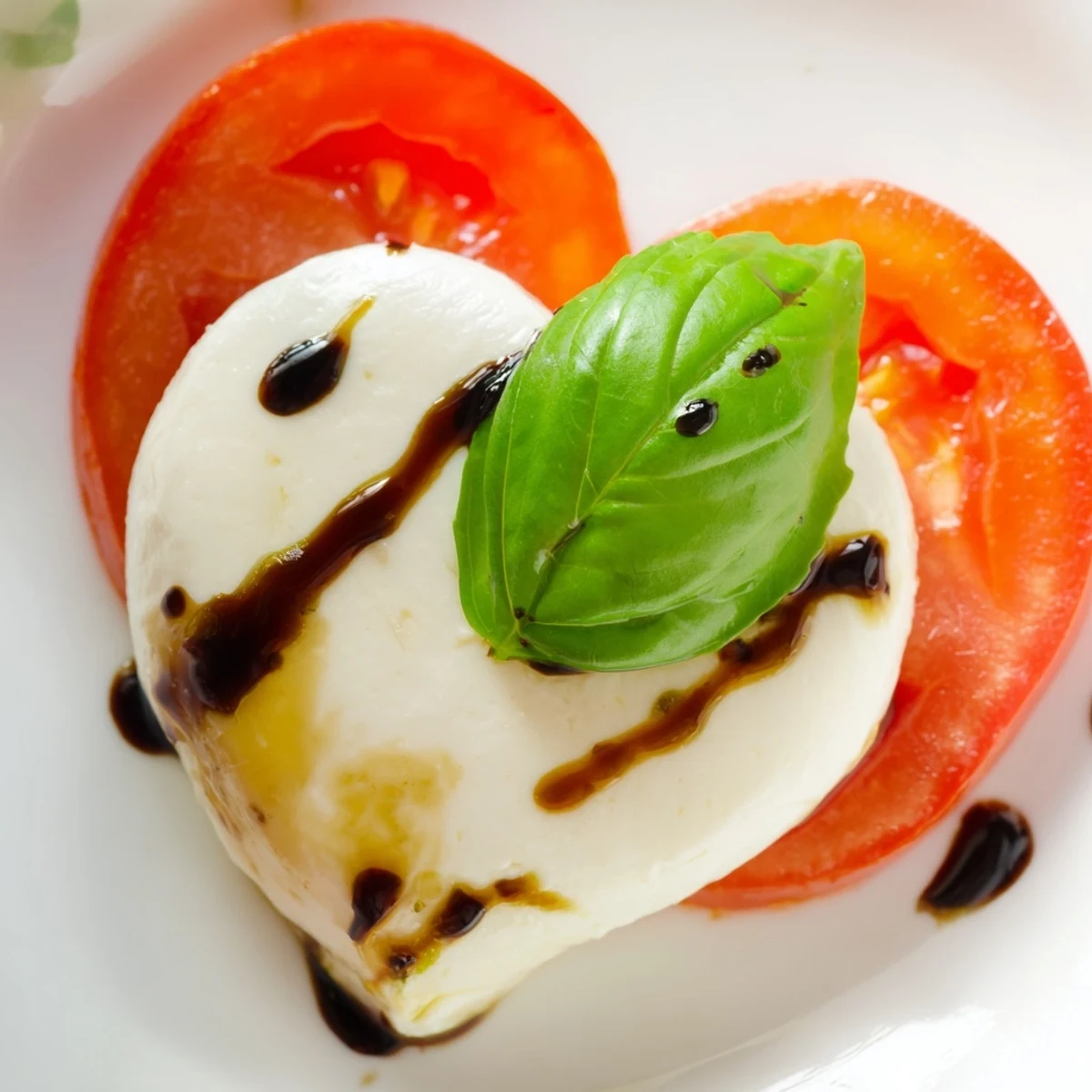 A romantic Valentine Heart Caprese Salad served with cherry tomatoes and fresh basil, ready for a special appetizer course or light dinner side.