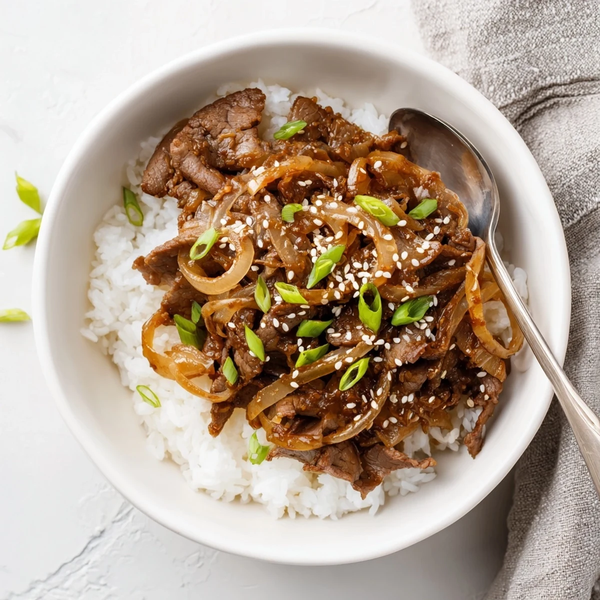 A close-up of a comforting Beef Bowl with Steamed Rice shows tender beef, sautéed onions, and a glossy sauce pooling around the aromatic jasmine rice.