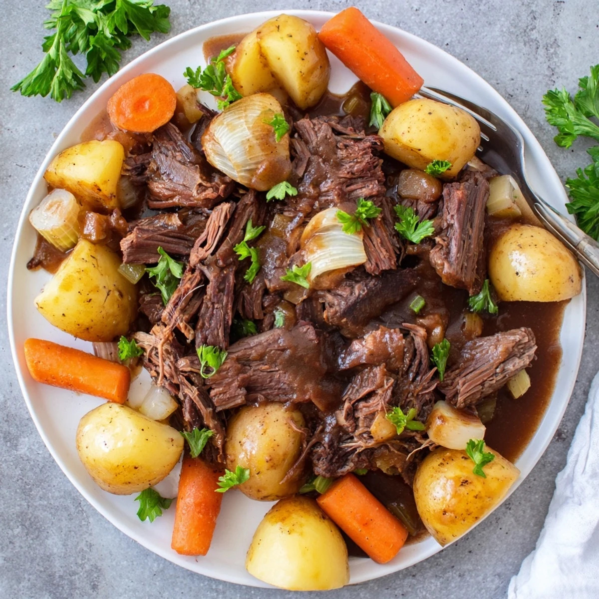 Slow cooker Slow Cooker Pot Roast shows melt-in-your-mouth beef with carrots and potatoes on a rustic plate.