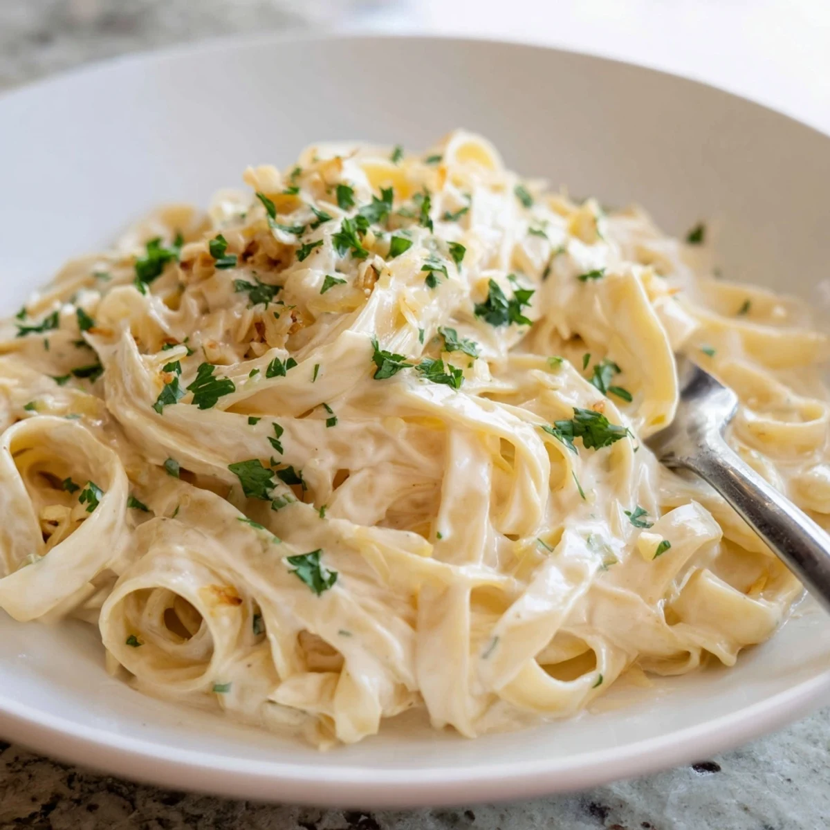 A bowl of creamy meal pasta sauce tossed with fettuccine, garnished with fresh parsley and grated Parmesan, ready to serve.