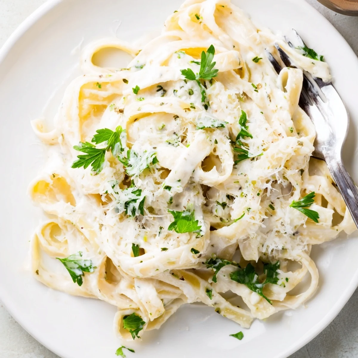 Close-up of creamy meal pasta sauce coating penne noodles, with steam rising and garlic pieces visible, suggesting a comforting Italian-inspired dish.