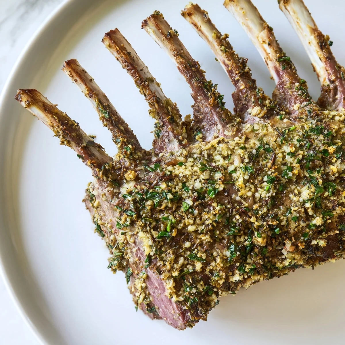 An elegant Romantic Roasted Rack of Lamb plated beside roasted potatoes and a glass of red wine, ready for a romantic dinner.