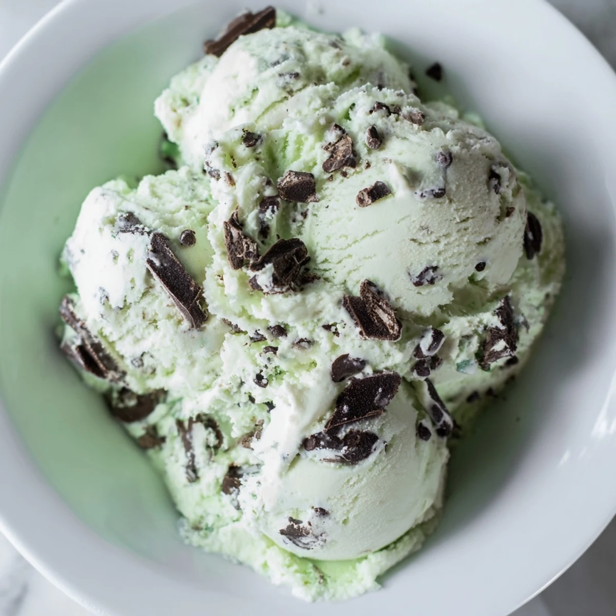 Freshly scooped St. Patrick's Day Mint Chocolate Chip Ice Cream reveals green cream and chopped dark chocolate in a homemade dessert.