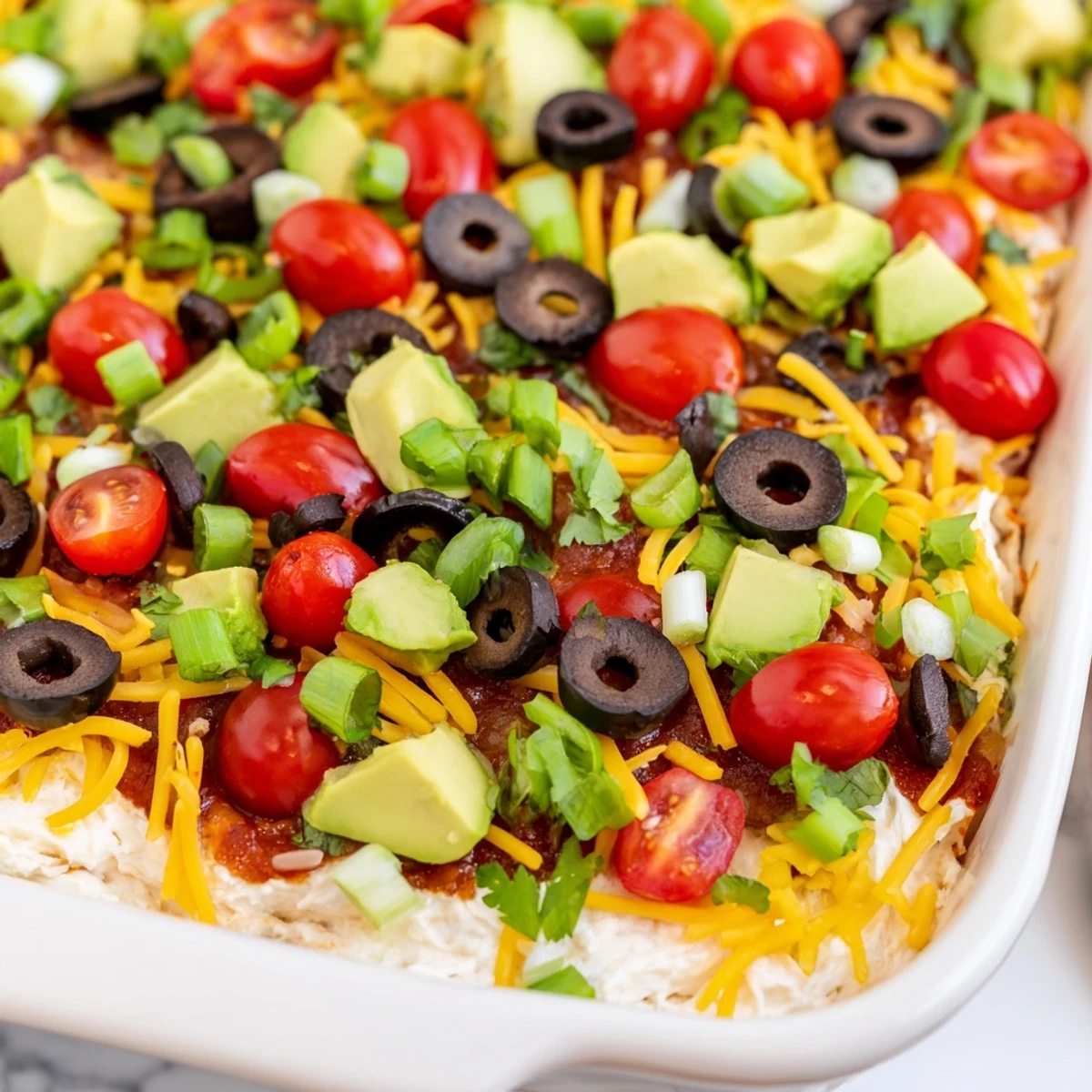 Freshly made Ultimate Layered Taco Dip with tortilla chips ready for a party platter.