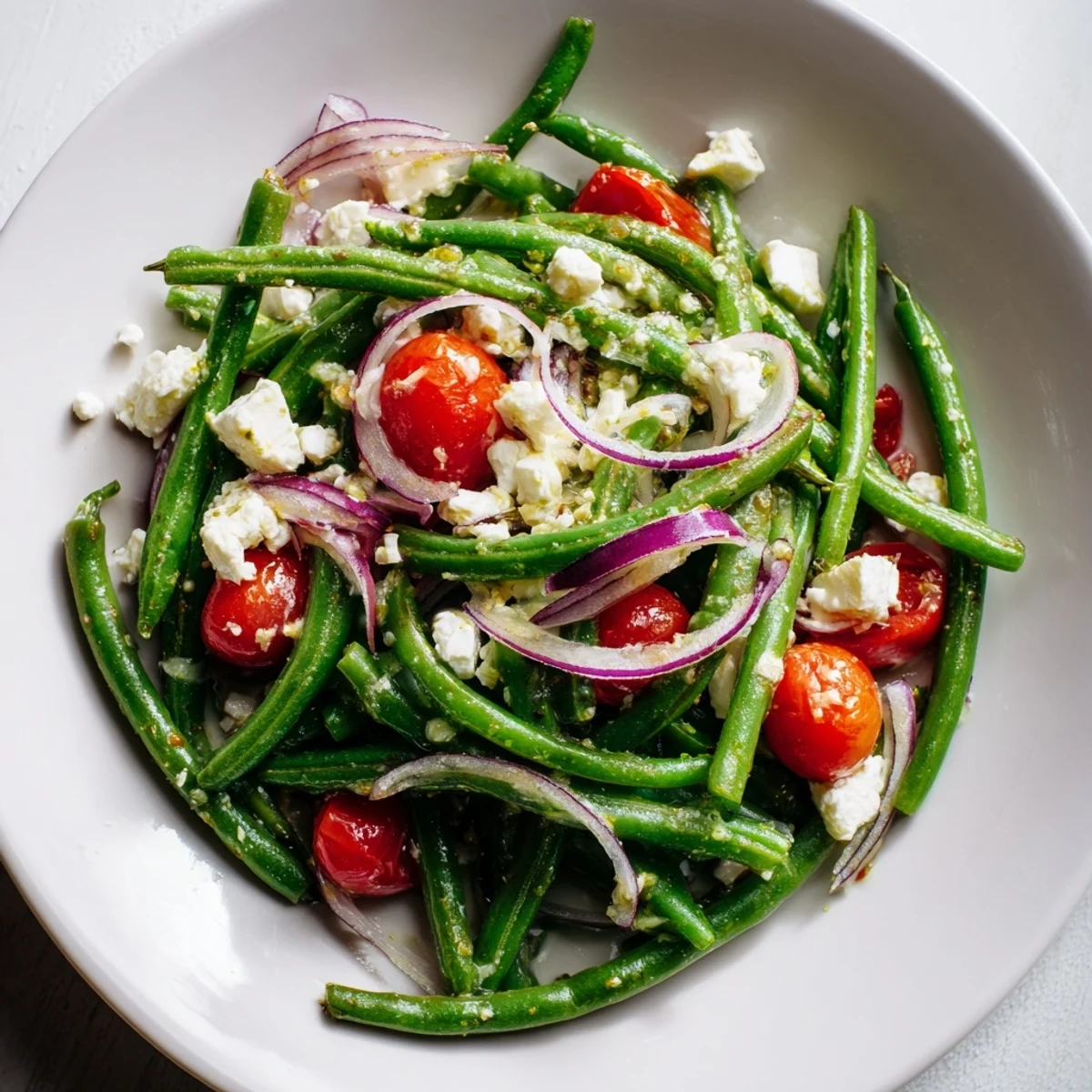 Close-up of Green Bean Salad with Feta showing juicy tomato halves, minced garlic, and olive oil drizzle ready for a quick summer side dish.