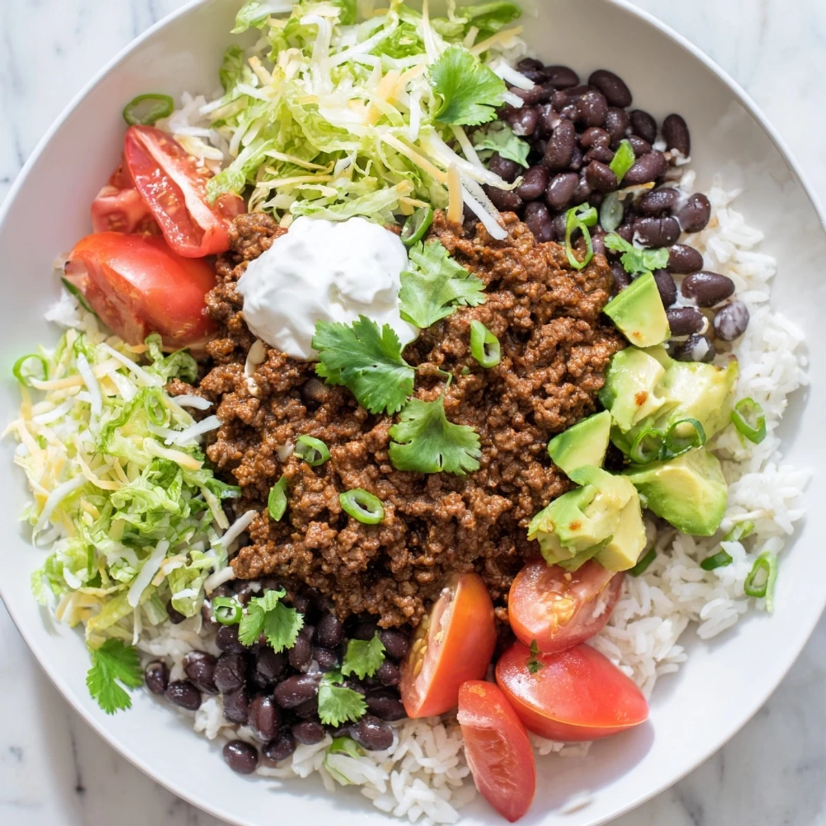 A close-up of Beef Burrito Bowls with Rice and Black Beans showing seasoned beef, fluffy rice, and vibrant toppings like avocado and tomatoes.