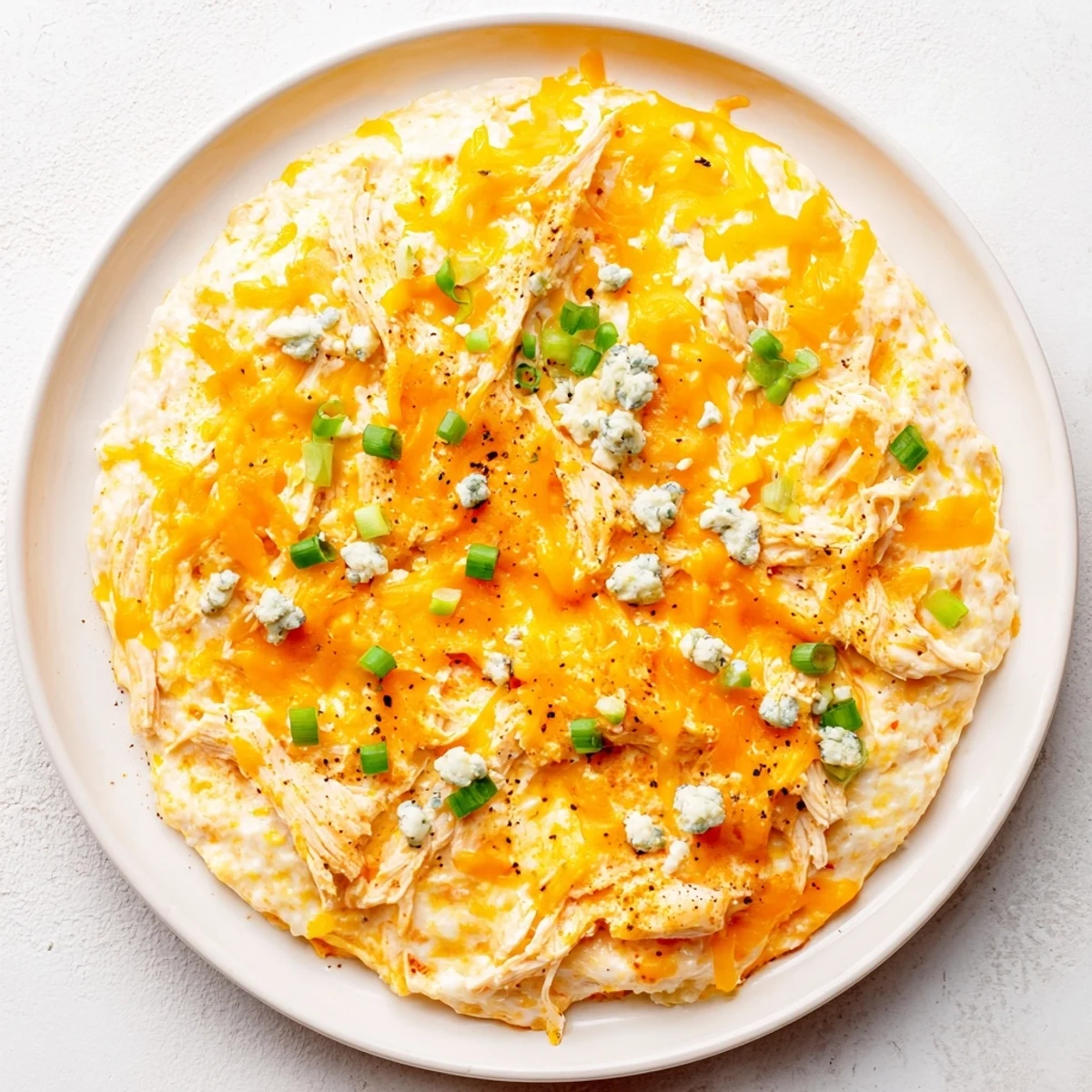 Spoon lifting a scoop of Keto Buffalo Chicken Dip, revealing its rich texture and served alongside crunchy celery sticks for game day.