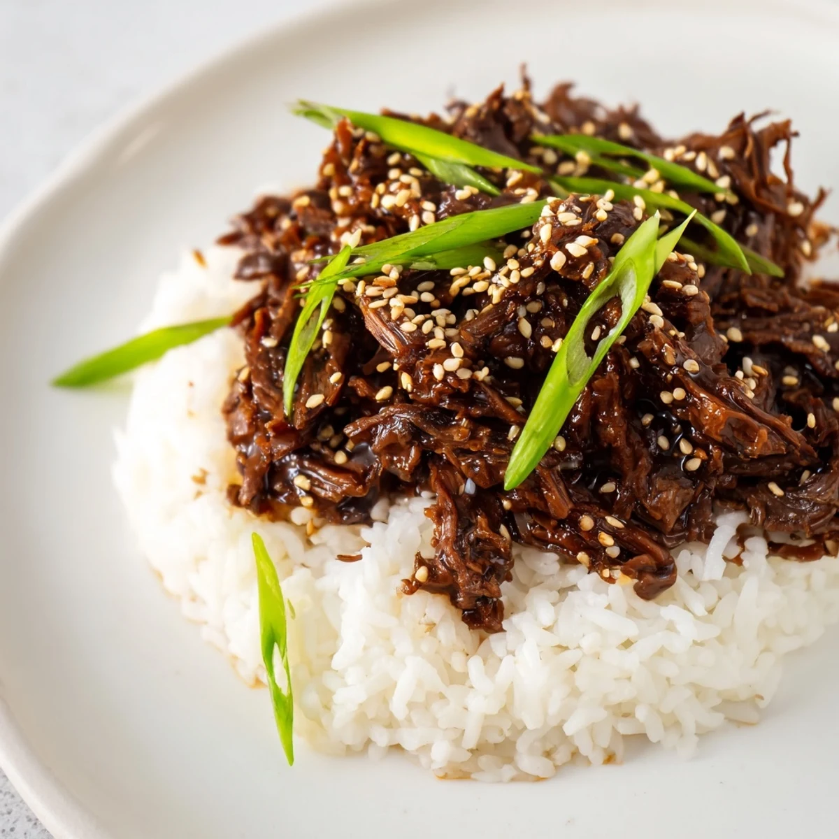 Slow cooker Korean beef simmering in a glossy, savory-sweet sauce with tender shredded chunks ready to serve over fluffy rice.