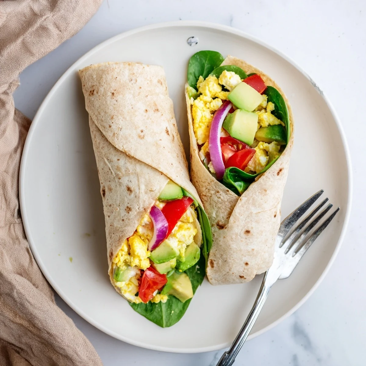 A close-up of a High Protein Breakfast Wrap with Cottage Cheese and Avocado sliced in half on a rustic plate.