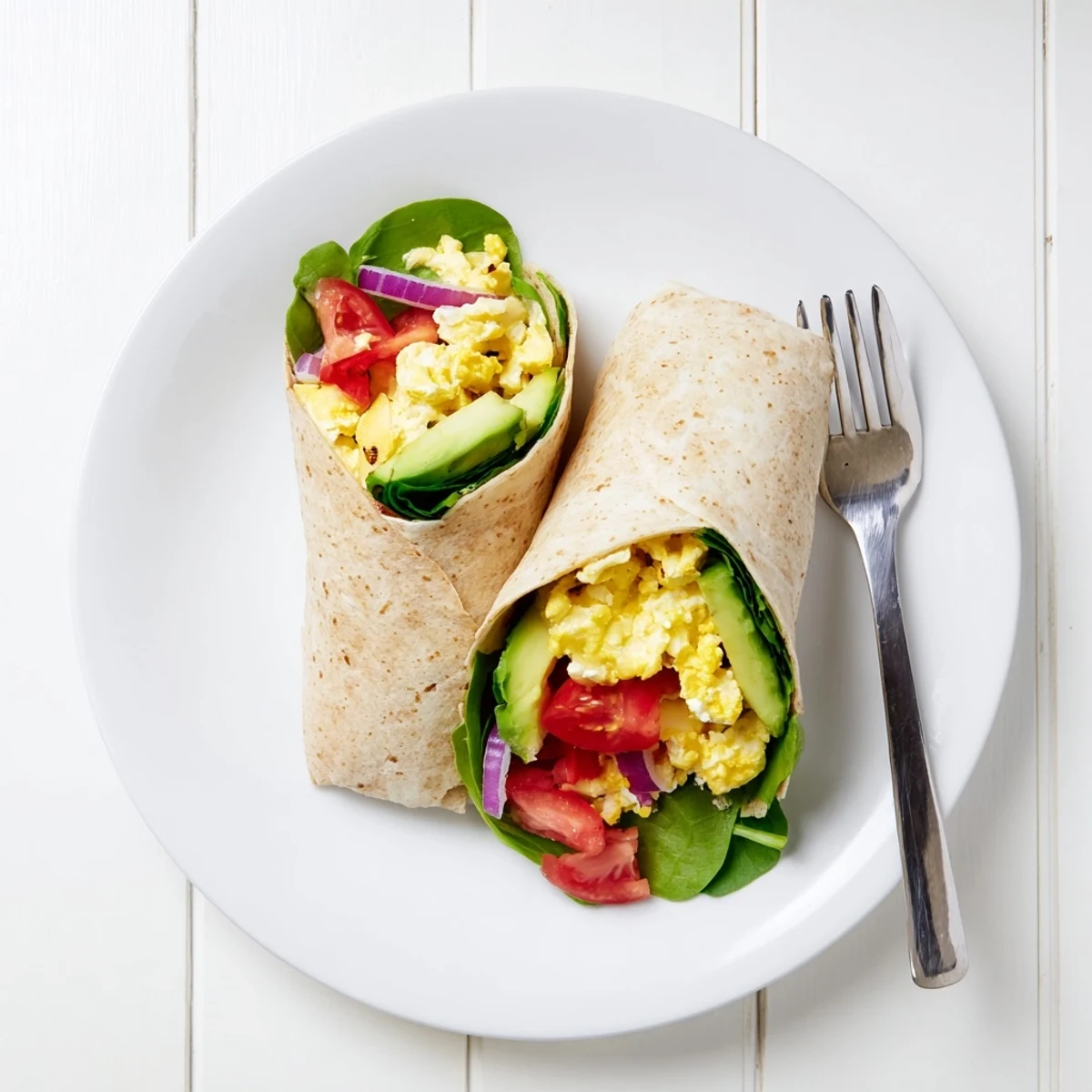 A wooden board displays two High Protein Breakfast Wraps with Cottage Cheese and Avocado and colorful fresh ingredients.
