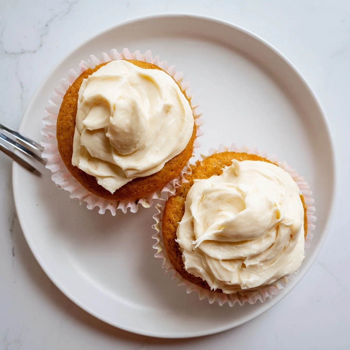 A hand holds a half-eaten Elderflower Cupcake, revealing the tender crumb and glistening elderflower syrup soak, with a delicate floral aroma evoking a spring afternoon tea.