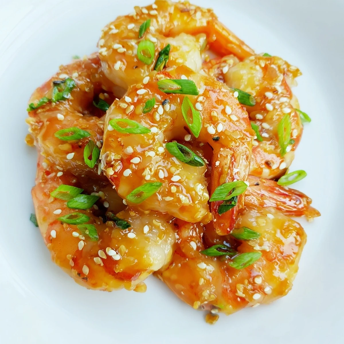 Juicy High Protein Honey Garlic Shrimp glisten in a skillet with green onions and sesame seeds, served over steamed rice for a quick meal.