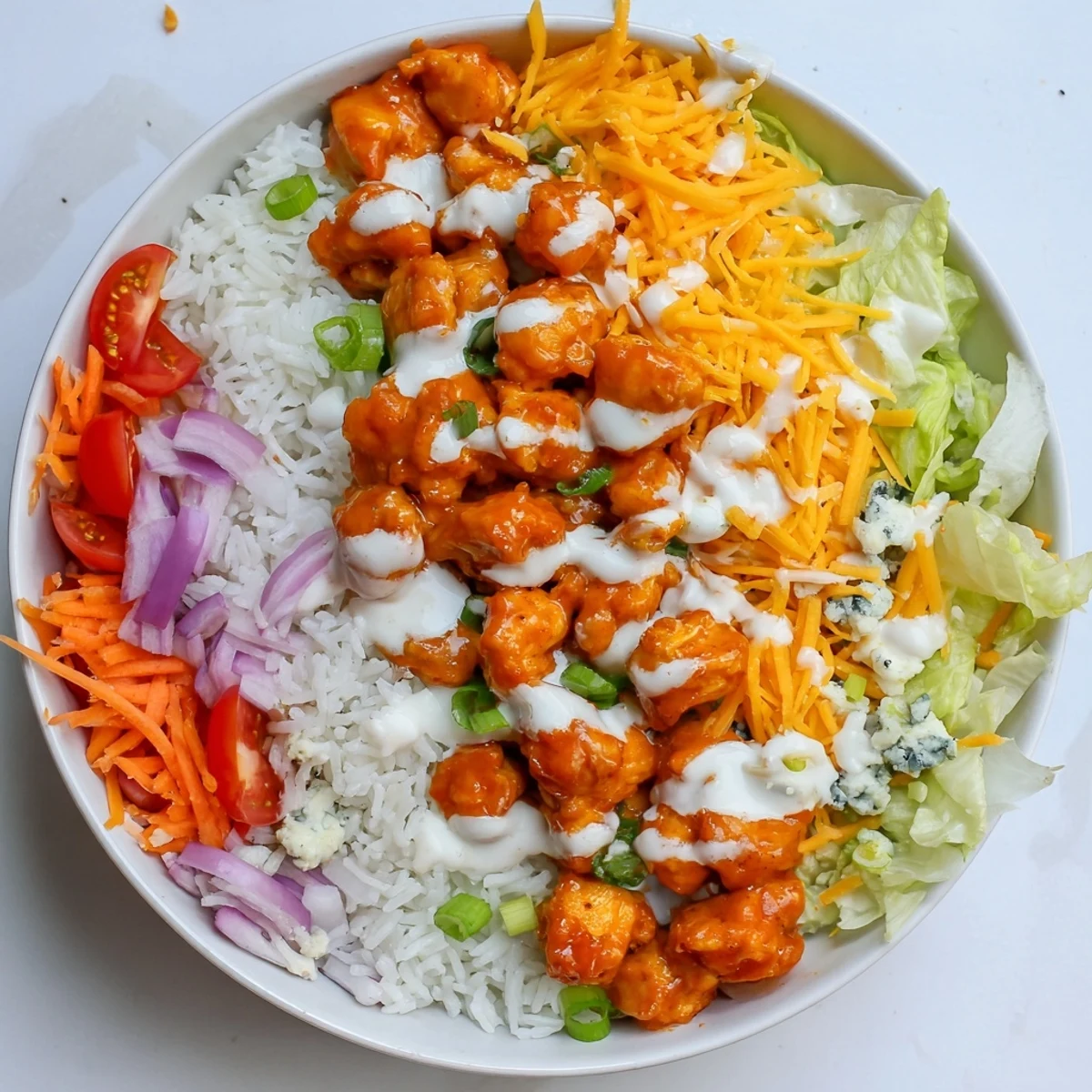 Colorful Buffalo Chicken Bowls with blue cheese crumbles and ranch sauce, served for dinner.