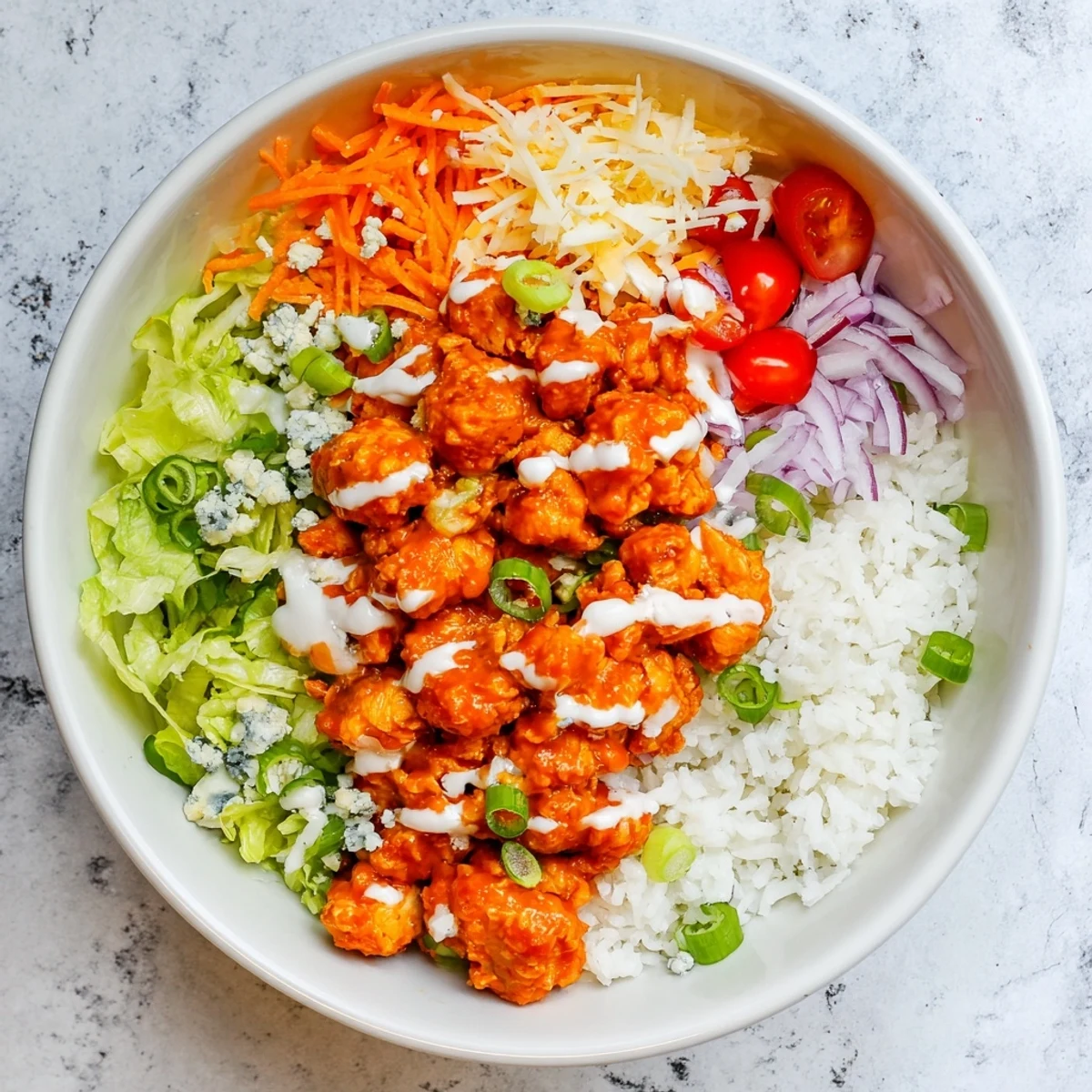 A close-up of Buffalo Chicken Bowls with red onion, tomatoes, and melted cheddar cheese.