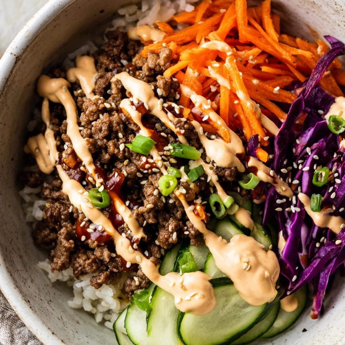 A close-up of a vibrant Korean Beef Bowl with Spicy Mayo, featuring tender beef and crunchy veggies on fluffy rice.