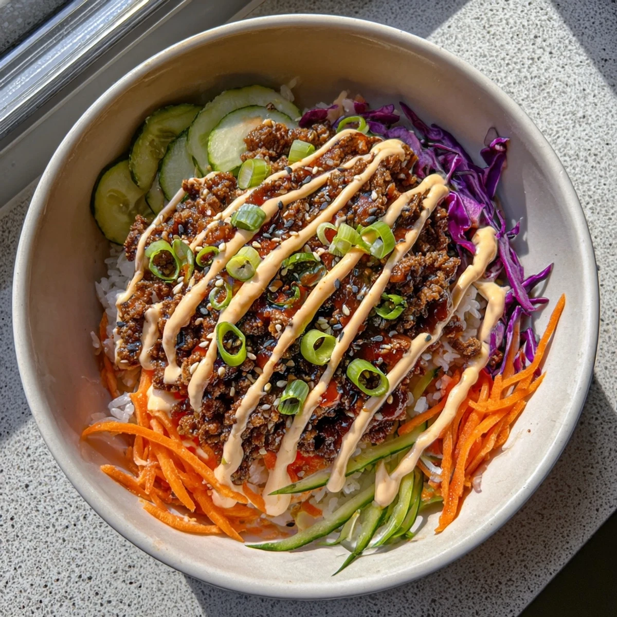 A colorful serving of Korean Beef Bowl with Spicy Mayo drizzled over the beef, paired with pickled carrots and cucumbers.