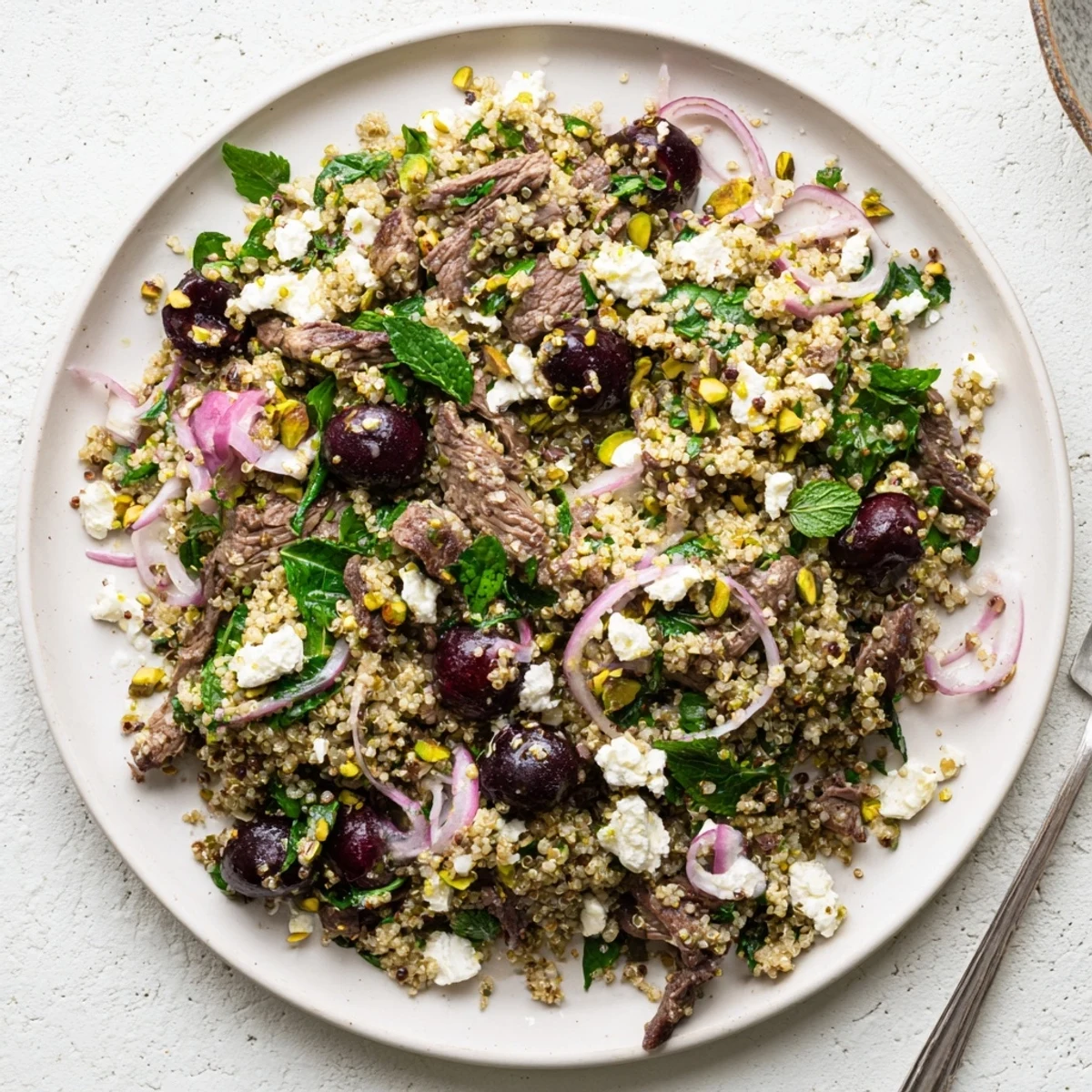 Bowl of Mediterranean cherry quinoa salad featuring spiced lamb and juicy red cherries