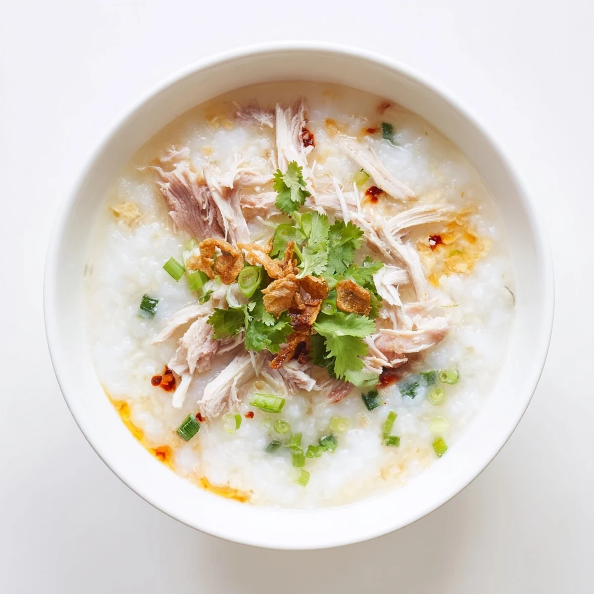 Creamy leftover Thanksgiving turkey congee topped with fresh scallions, cilantro, and crispy shallots