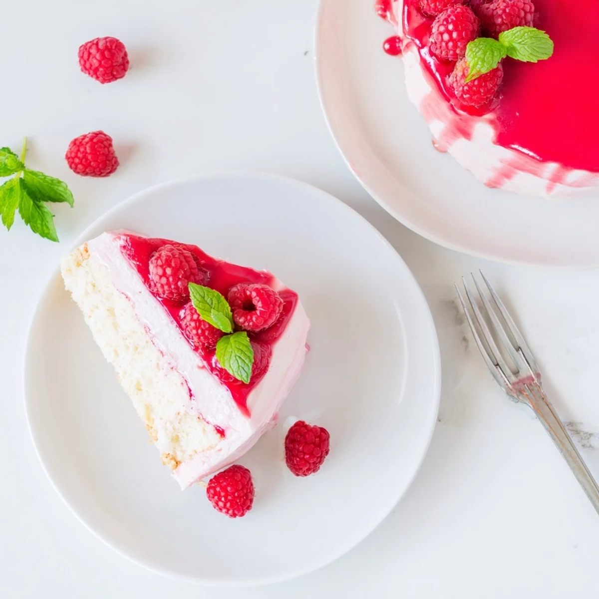 Beautiful slice of raspberry mousse cake revealing vibrant pink layers and almond sponge texture