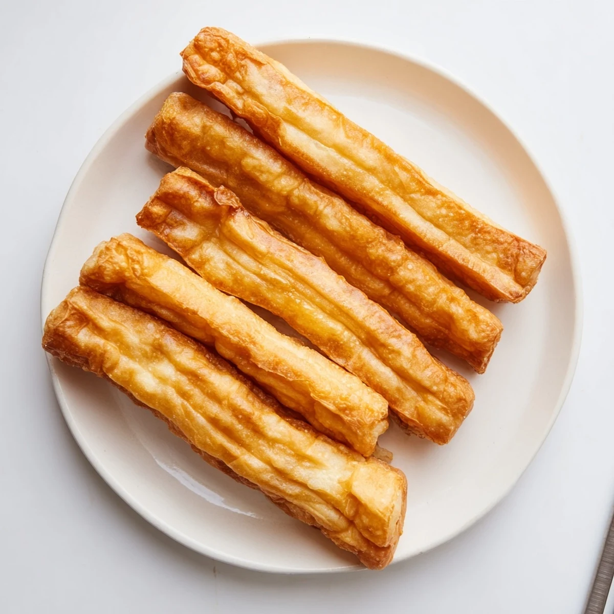 Crispy hollow Youtiao fried dough sticks arranged on wire cooling rack
