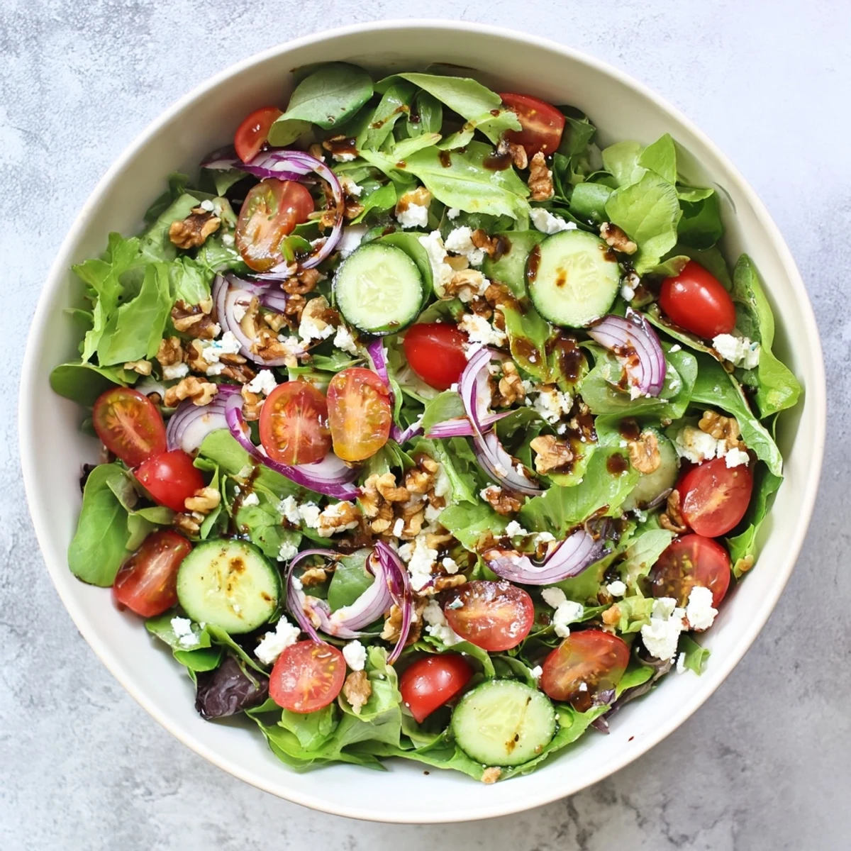 Fresh spring mix salad with balsamic honey dressing drizzled over vibrant cherry tomatoes and crisp cucumber slices
