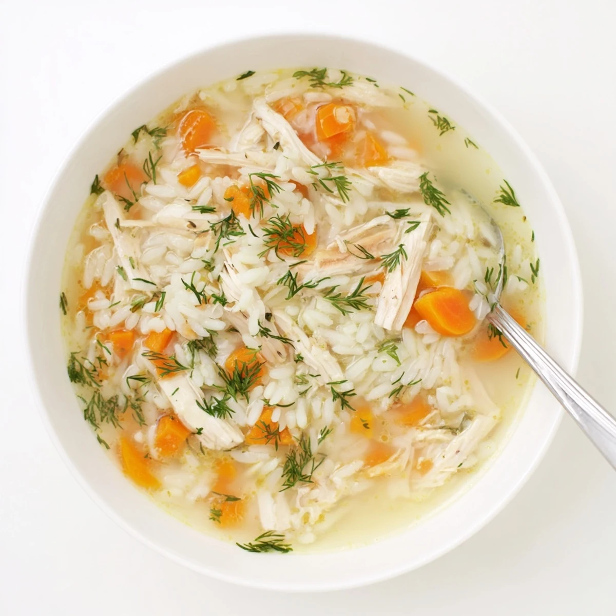 Creamy avgolemono Greek lemon chicken soup with tender shredded chicken and fluffy white rice in a bright golden egg-lemon broth garnished with fresh dill