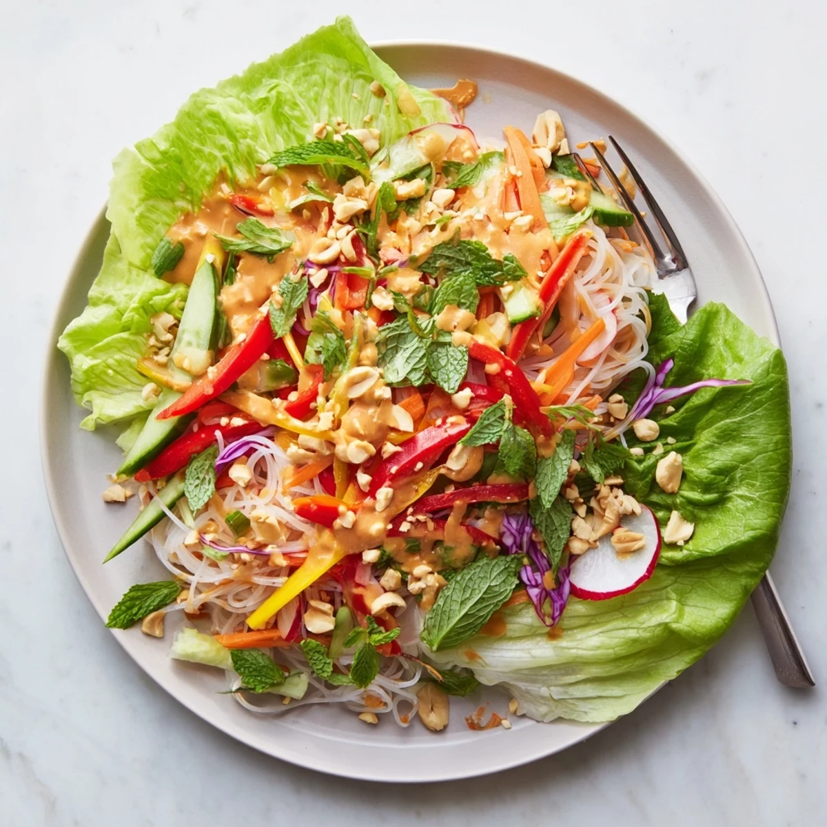 Colorful spring roll salad with peanut dressing featuring crisp julienned vegetables, vermicelli noodles, and fresh herbs