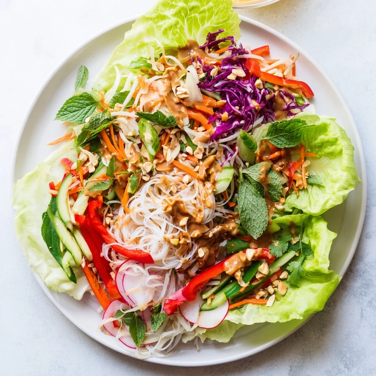 Vibrant Vietnamese-inspired spring roll salad drizzled with creamy peanut dressing over shredded cabbage and crunchy vegetables