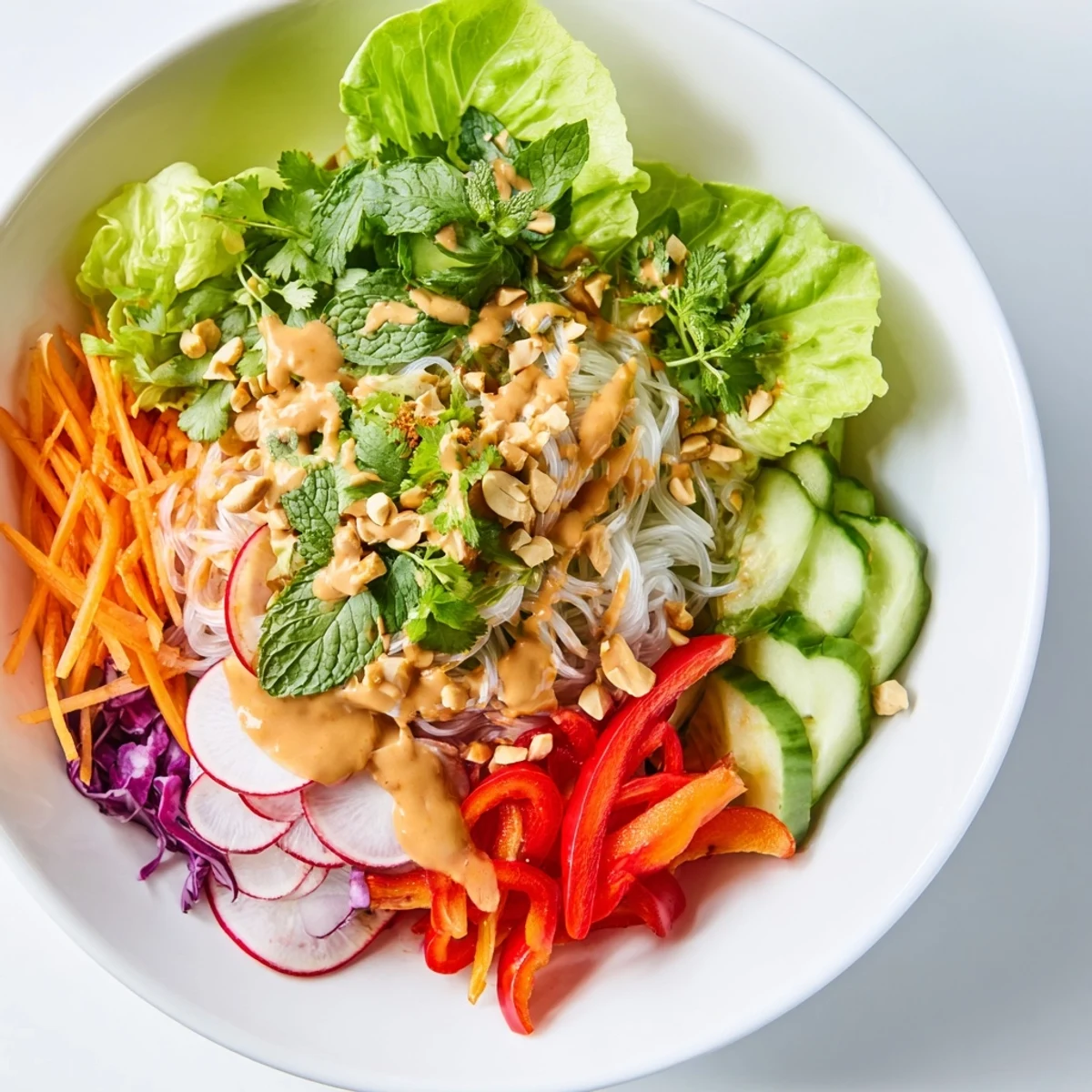 Fresh spring roll salad with peanut dressing arranged in lettuce cups topped with roasted peanuts and fragrant herbs