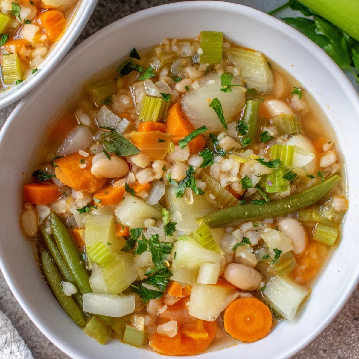 Comforting stone soup featuring diced carrots, potatoes, and green beans served in a white ceramic bowl