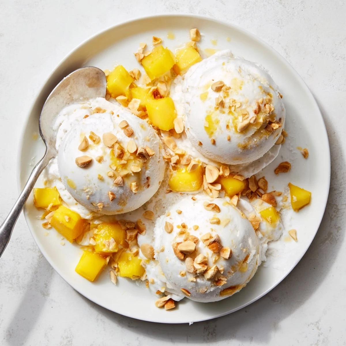 Creamy scoops of Thai coconut milk ice cream garnished with toasted flakes and diced mango
