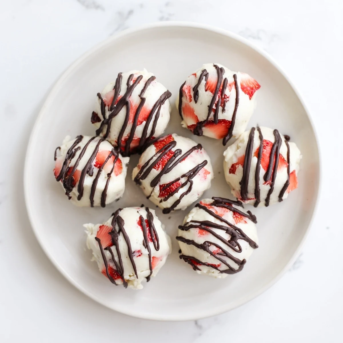 Creamy Greek yogurt strawberry protein bites topped with fresh diced red berries on parchment paper