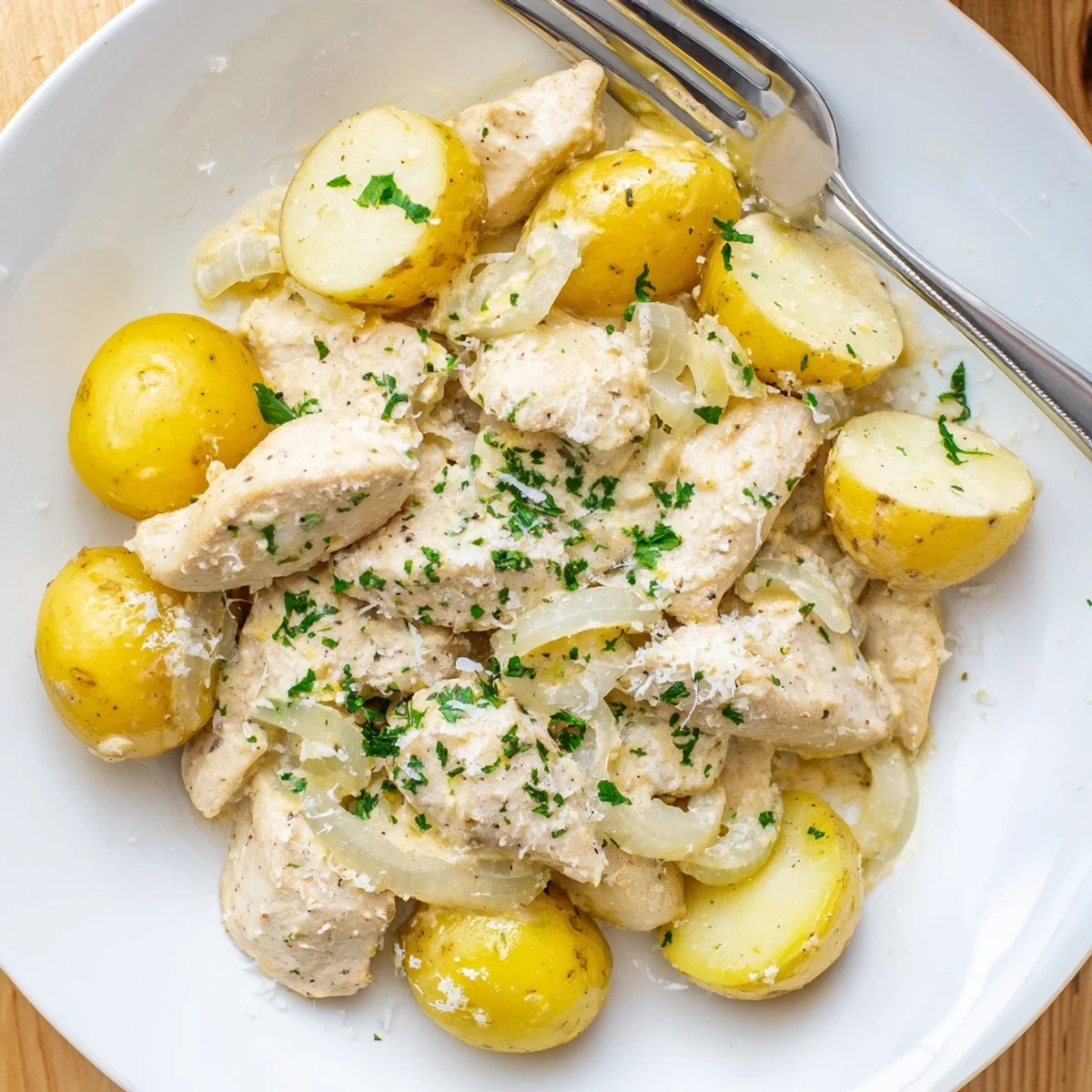 Creamy garlic parmesan chicken and potatoes slow cooked to perfection with fresh parsley garnish