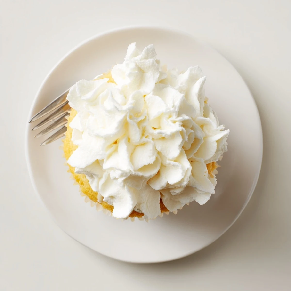 Golden homemade vanilla cupcakes with tall peaks of sweet buttercream and colorful sprinkles for decoration