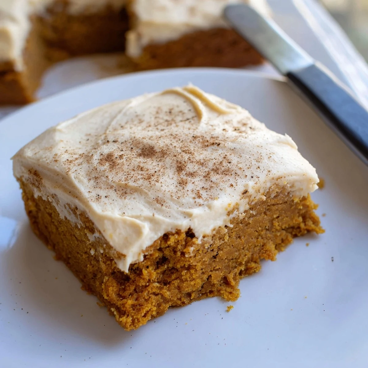 Warm spiced pumpkin bars with cream cheese frosting cut into generous squares