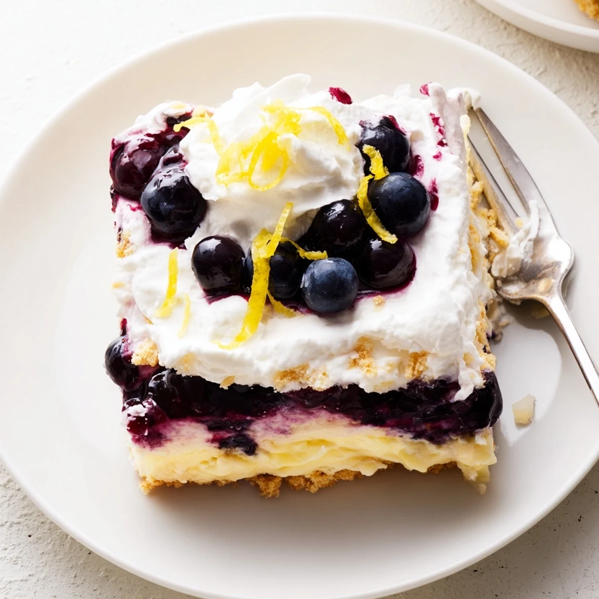 Chilled lemon blueberry lasagna recipe with whipped cream topping and fresh blueberry garnish.