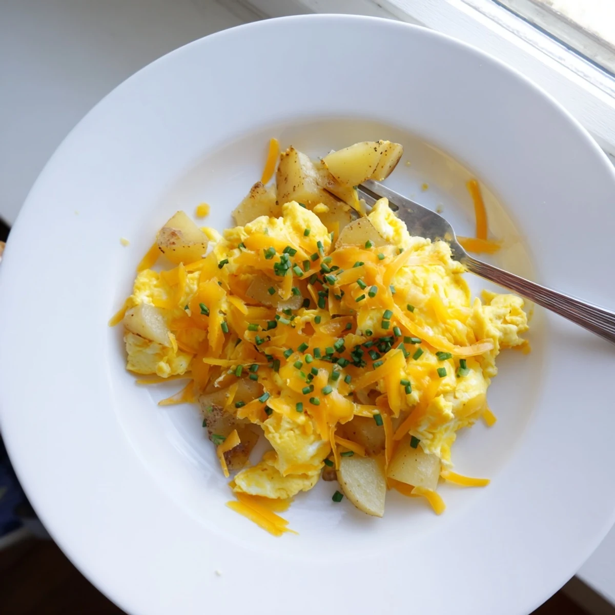 Hearty breakfast skillet of fluffy scrambled eggs with tender golden potatoes and gooey melted cheese
