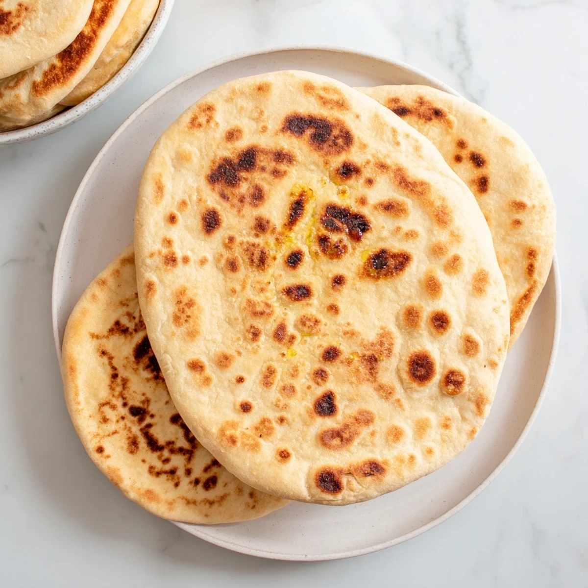 Freshly cooked Turkish Bazlama bread resting on wooden board with brushed olive oil glistening