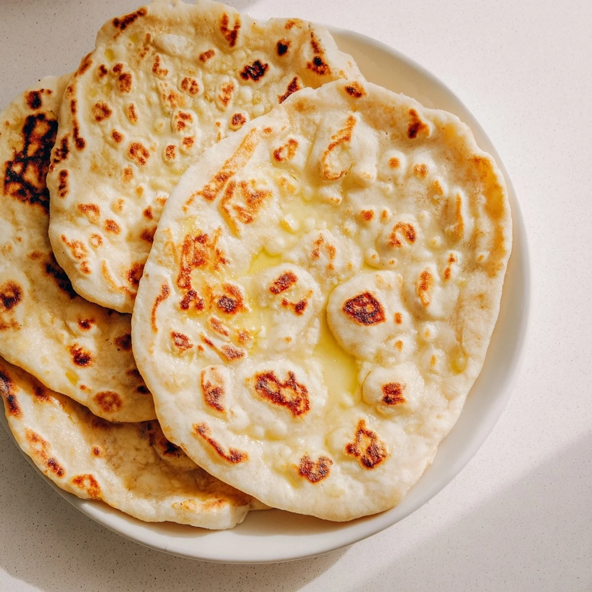 Warm Turkish Bazlama flatbread stack wrapped in kitchen towel ready for serving with dips