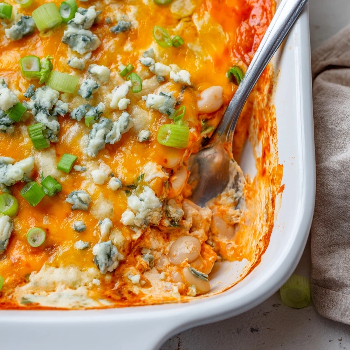 Creamy white bean buffalo dip with melted cheddar cheese and blue cheese crumbles